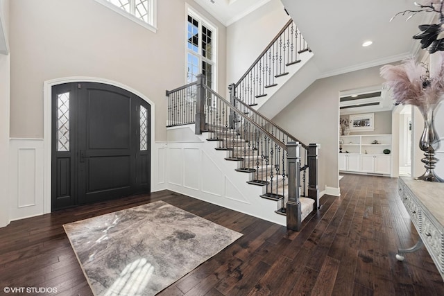 entryway with arched walkways, crown molding, and plenty of natural light