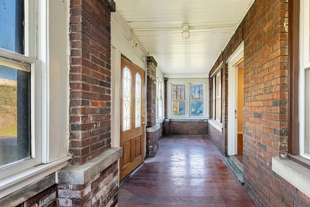unfurnished sunroom featuring wood finished floors and brick wall