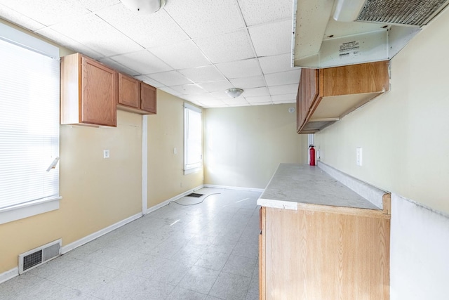 kitchen with visible vents, light countertops, baseboards, and under cabinet range hood