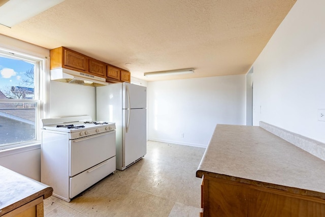 kitchen with a textured ceiling, baseboards, under cabinet range hood, white appliances, and brown cabinetry