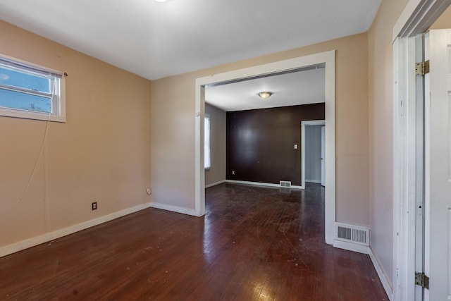 unfurnished room with baseboards, visible vents, and hardwood / wood-style flooring