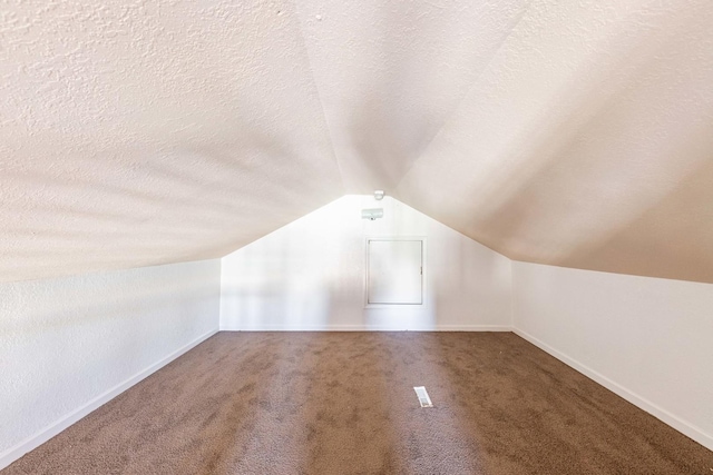 additional living space with baseboards, a textured ceiling, carpet flooring, and vaulted ceiling
