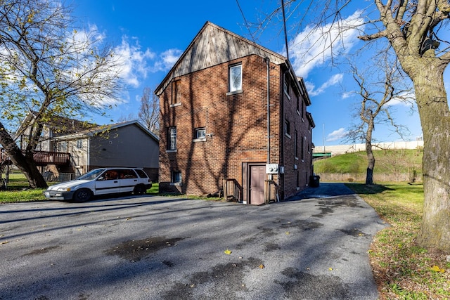 view of property exterior featuring brick siding and aphalt driveway