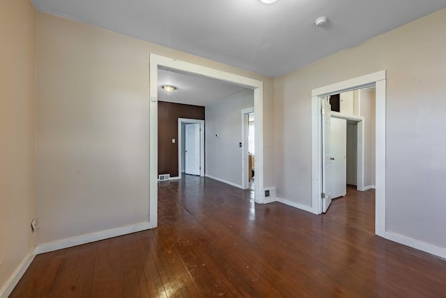 unfurnished room featuring visible vents, hardwood / wood-style flooring, and baseboards