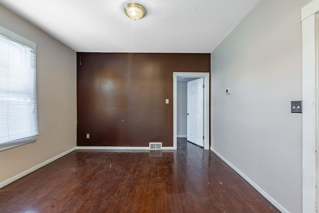 unfurnished room with visible vents, hardwood / wood-style flooring, and baseboards