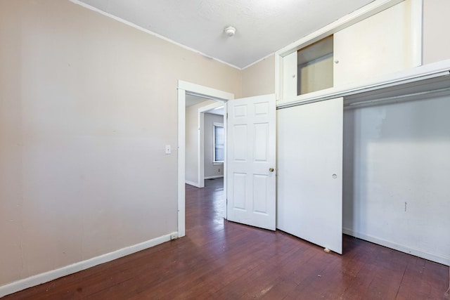 unfurnished bedroom with hardwood / wood-style floors, baseboards, a closet, and crown molding