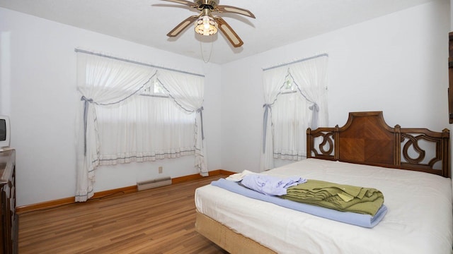 bedroom featuring baseboards, baseboard heating, a ceiling fan, and wood finished floors