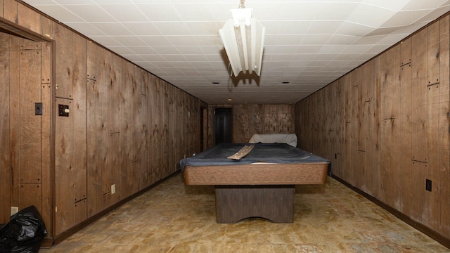 bedroom with baseboards, wooden walls, and pool table