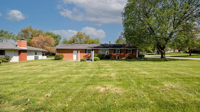 rear view of house featuring a yard and brick siding