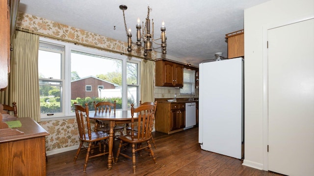 dining room with wallpapered walls, a notable chandelier, plenty of natural light, baseboards, and dark wood-style floors