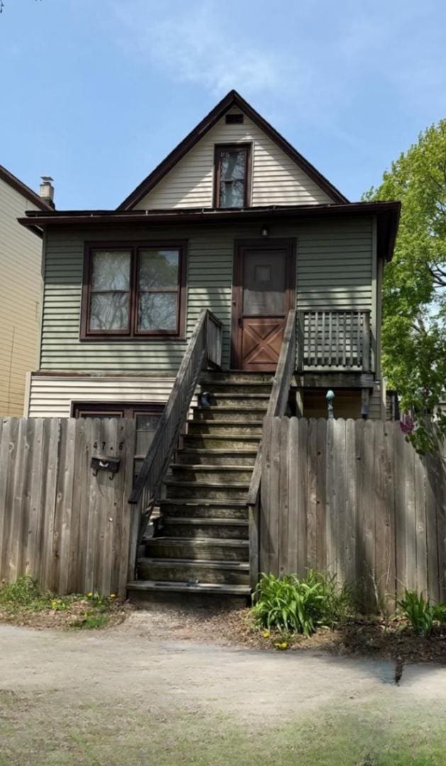 back of property with fence and stairs