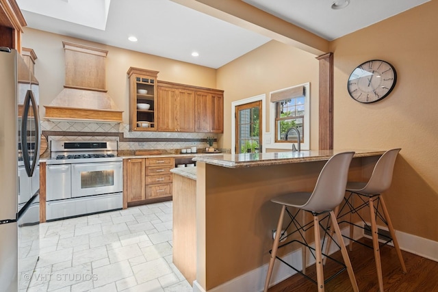 122 Logan Ave, Geneva, IL 60134 - kitchen featuring stainless steel appliances, premium range hood, a kitchen bar, backsplash, and light stone counters