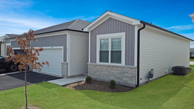 946 Partridge Cir, Marengo, IL 60152 - view of side of home with central AC unit, a garage, aphalt driveway, a yard, and stone siding