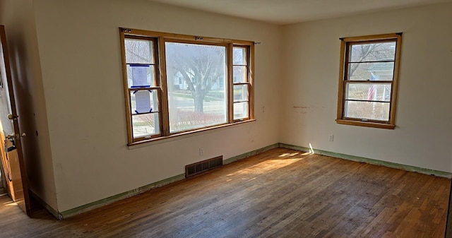 unfurnished room featuring visible vents, wood finished floors, and baseboards