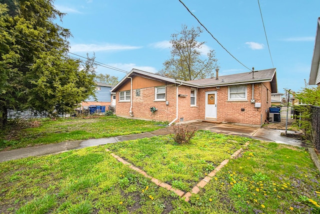 rear view of property with brick siding, a patio, fence, and a lawn