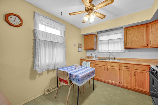kitchen featuring a ceiling fan, visible vents, a sink, light countertops, and black range oven