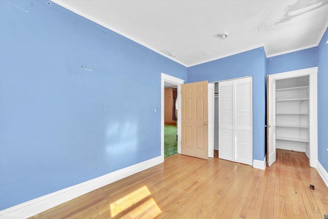 unfurnished bedroom featuring a closet, baseboards, and wood finished floors