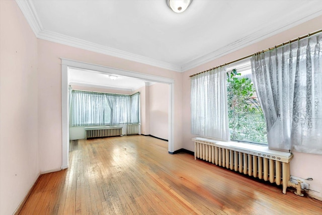 unfurnished room with wood-type flooring, a wealth of natural light, and radiator heating unit