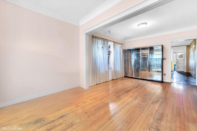 spare room featuring a healthy amount of sunlight, baseboards, ornamental molding, and wood-type flooring
