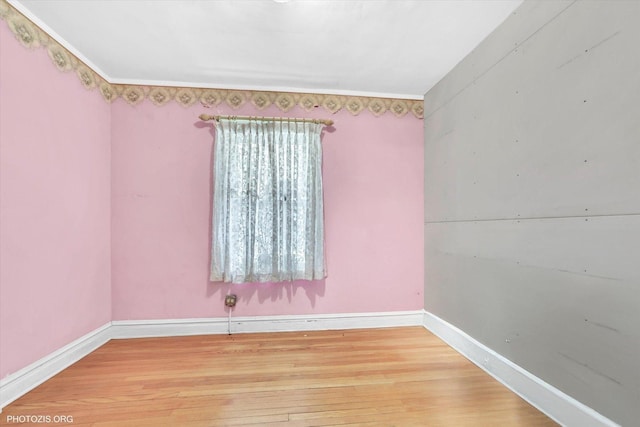 spare room with crown molding, baseboards, and wood finished floors