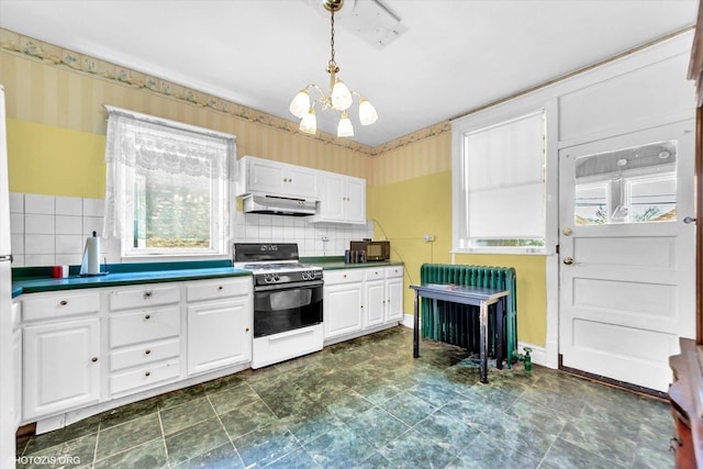 kitchen with dark countertops, gas range, wallpapered walls, white cabinetry, and under cabinet range hood