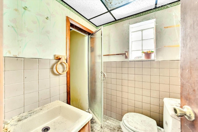 bathroom with a sink, tile walls, walk in shower, and toilet