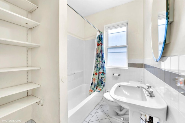 full bath with tile patterned flooring, tile walls, a wainscoted wall, a sink, and shower / tub combo
