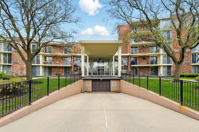 view of property with concrete driveway, fence, and an attached garage