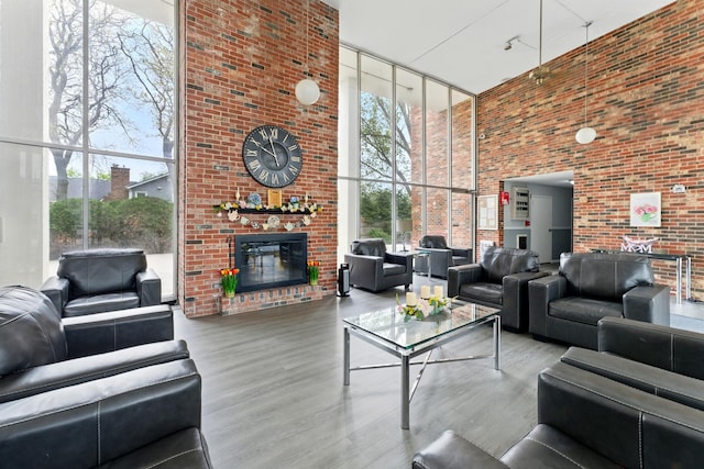 living room with expansive windows, wood finished floors, a fireplace, and a high ceiling