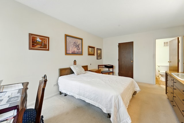 bedroom featuring ensuite bathroom, light carpet, visible vents, and a sink