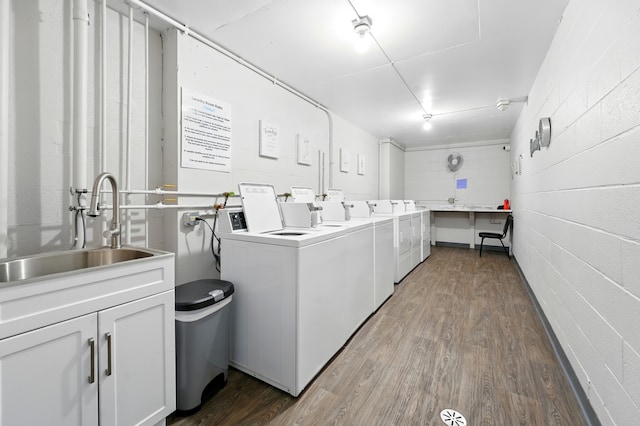 common laundry area featuring washing machine and clothes dryer, wood finished floors, and a sink