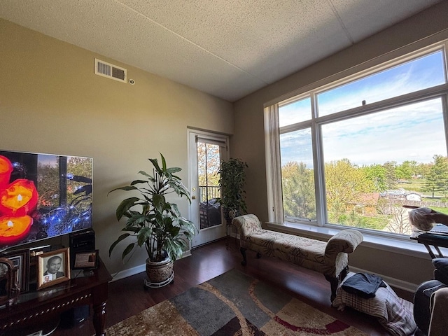 living area with wood finished floors, lofted ceiling, baseboards, and a textured ceiling