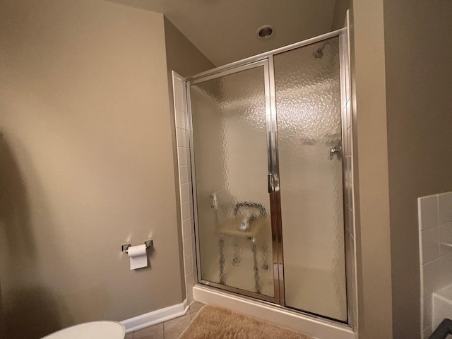 bathroom featuring a shower stall, tile patterned flooring, toilet, and baseboards