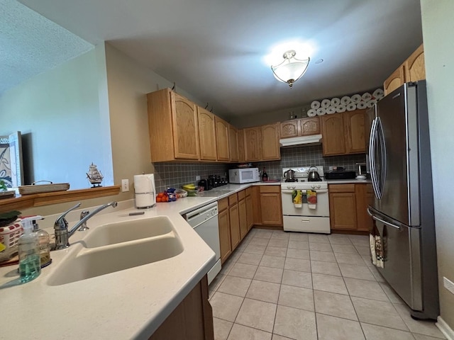 kitchen featuring white appliances, a sink, under cabinet range hood, light tile patterned flooring, and decorative backsplash