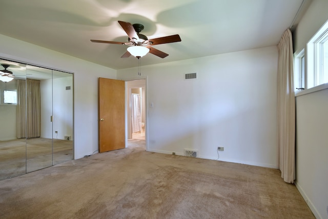 unfurnished bedroom featuring a ceiling fan, carpet, a closet, and visible vents