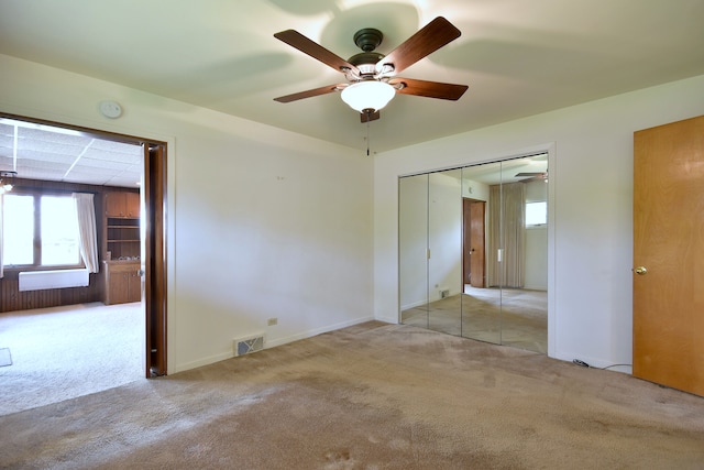 empty room with carpet flooring, a ceiling fan, baseboards, and visible vents