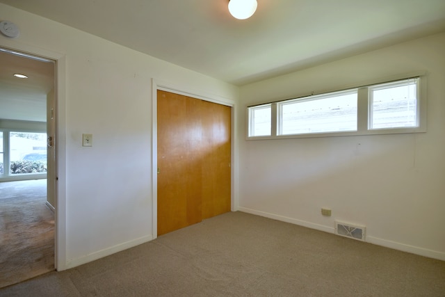 unfurnished bedroom with baseboards, carpet, a closet, and visible vents