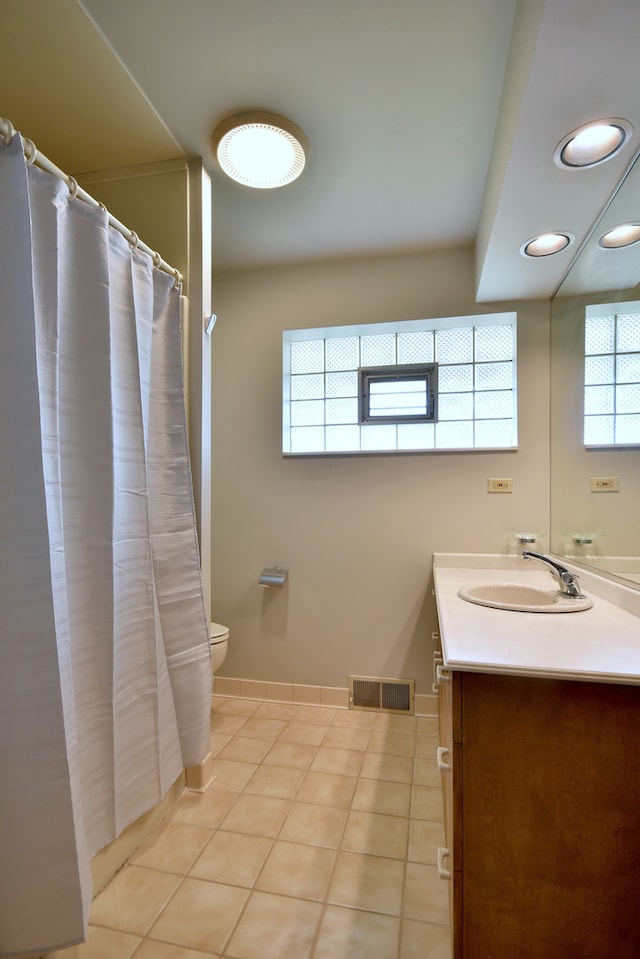 bathroom with visible vents, vanity, toilet, baseboards, and tile patterned floors