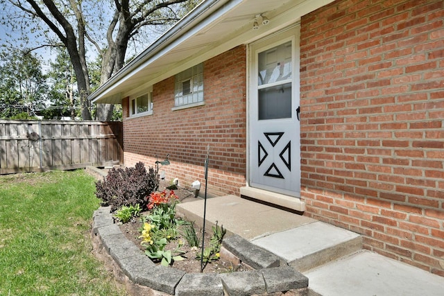 property entrance with fence and brick siding