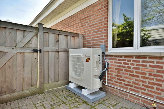 details with a gate, ac unit, and brick siding