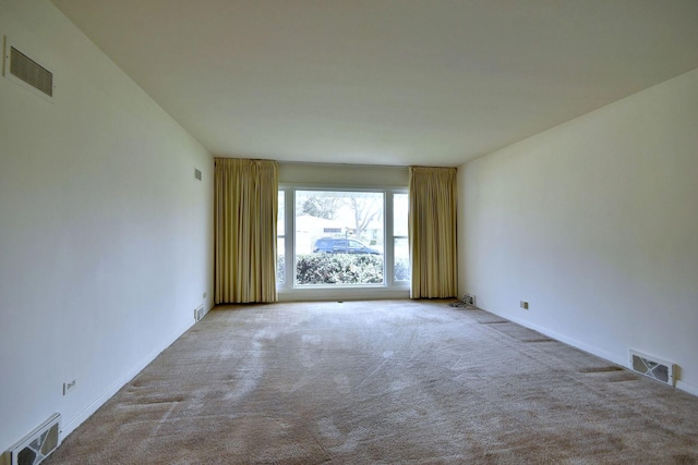 carpeted spare room featuring visible vents and baseboards