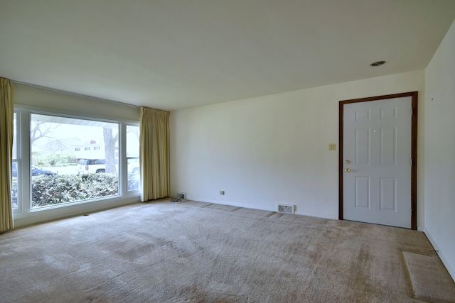 carpeted empty room featuring baseboards and visible vents