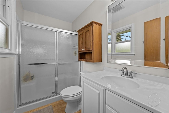 full bath with vanity, toilet, a shower stall, wood finished floors, and visible vents