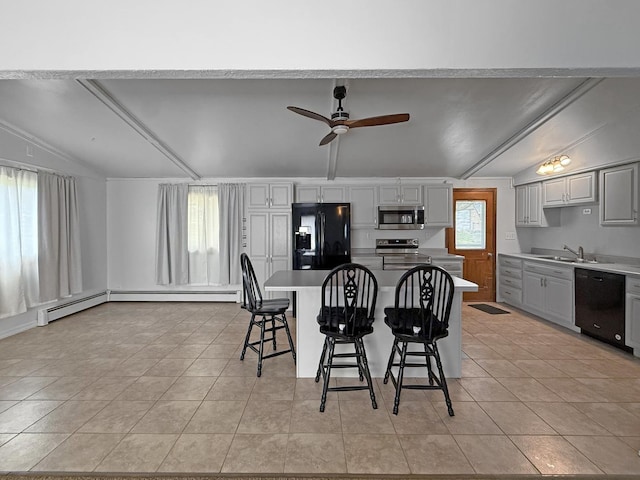 kitchen featuring ceiling fan, a kitchen island, black appliances, a breakfast bar, and light tile patterned flooring