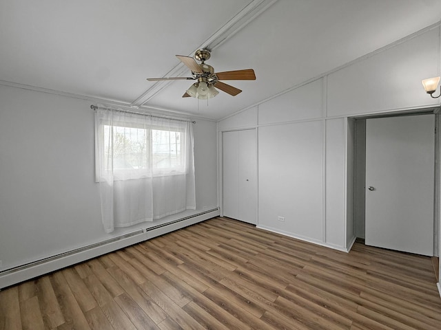 unfurnished bedroom with a closet, wood finished floors, lofted ceiling, baseboard heating, and a ceiling fan