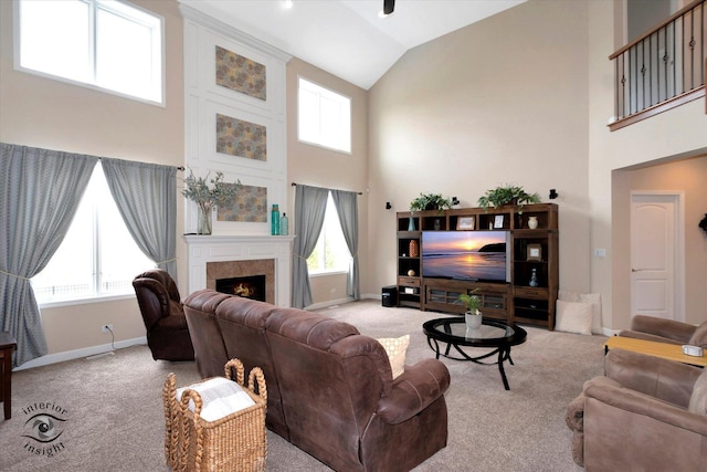 living area featuring baseboards, carpet flooring, plenty of natural light, and high vaulted ceiling