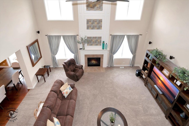 carpeted living room with a fireplace, baseboards, and a towering ceiling