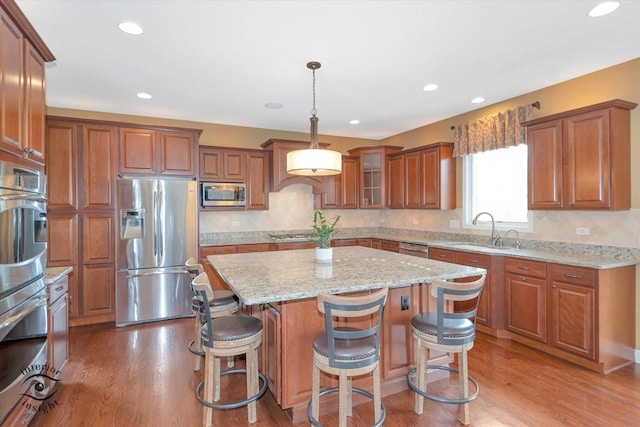 kitchen with brown cabinets, stainless steel appliances, a kitchen island, and a sink