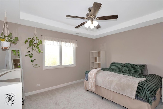 bedroom with light colored carpet, a raised ceiling, and baseboards