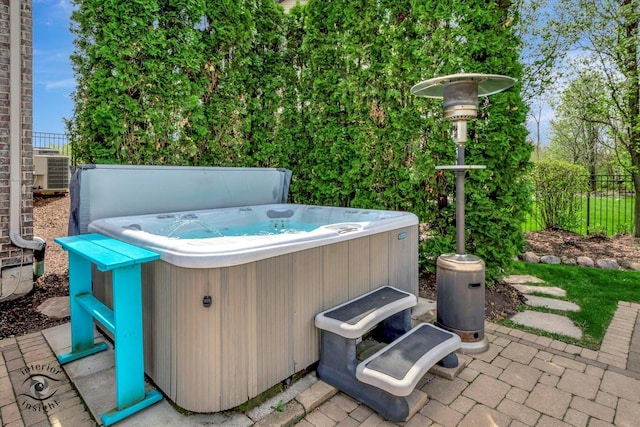 view of patio featuring central AC, a hot tub, and fence